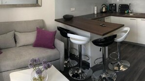A modern kitchen with a central island, bar stools, and a dining table. - Apartment Sara by Interhome (Zadar)