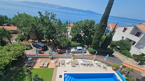 A pool area with lounge chairs and umbrellas, surrounded by greenery and overlooking a body of water. - Wohnung mit Meerblick, 200m vom Strand entfernt by Interhome (Novi Vinodolski)