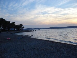 A beach with a rocky shoreline, a lighthouse in the distance, and a calm sea.