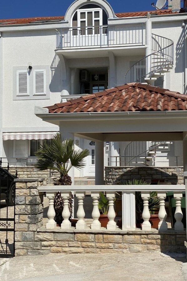 Un bâtiment à deux étages doté d’un balcon, d’un mur en pierre et d’un toit recouvert de tuiles.