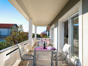 A balcony with a table and chairs, a bottle, and a glass. - Apartment Sukosan by Interhome (Debeljak)