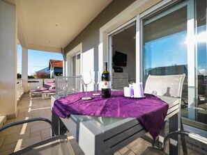 A balcony with a table set for two, a bottle of wine, and candles. - Apartment Sukosan by Interhome (Debeljak)