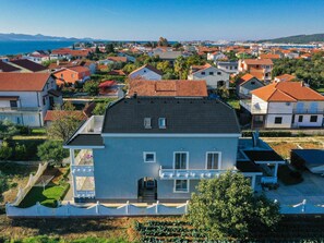 A residential area with houses featuring red-tiled roofs and a large building with a dark roof and white walls. - Apartment Sukosan by Interhome (Debeljak)