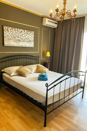 A neatly made bed with a metal frame, a wall-mounted air conditioner, a chandelier, and a painting above the bed. - mit Privatpool neben dem Strand by Interhome (Omiš)