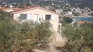 A two-story building with a beige facade, a red-tiled roof, and a staircase leading to the entrance. - mit Blick auf das Wasser by Interhome (Marina)