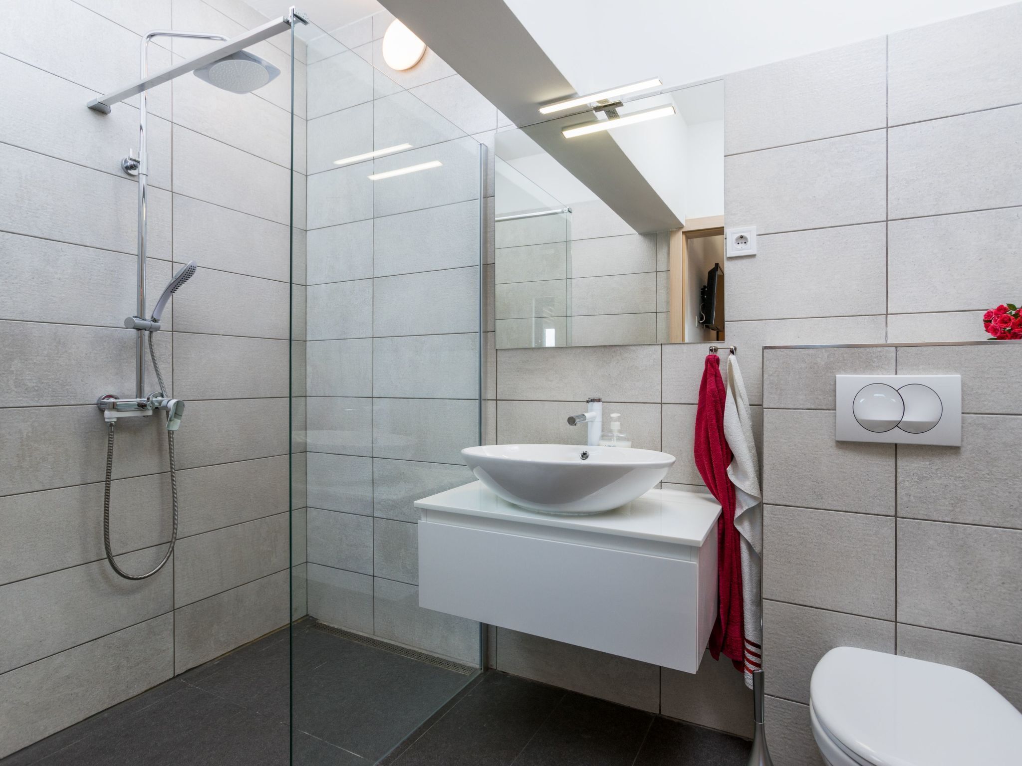 A modern bathroom with a glass-enclosed shower, a white sink, and a toilet.
