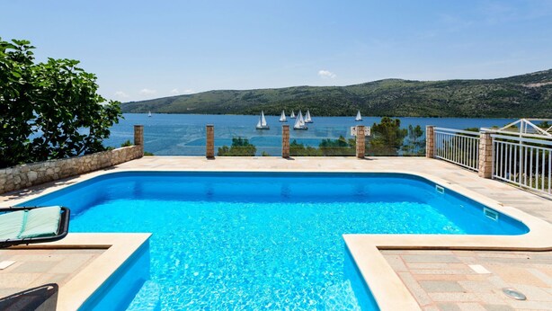 Una piscina con vista al mar y a veleros.