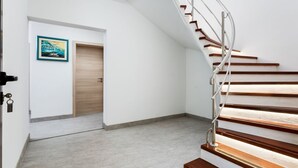 Un interior moderno con una escalera curva, una puerta de madera y un cuadro en la pared.