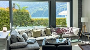 A modern living room with a sofa, coffee table, and a view of a mountainous landscape through large windows.