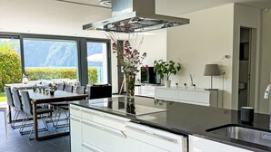 A modern kitchen with a large island, white cabinetry, and a view of the outdoors.