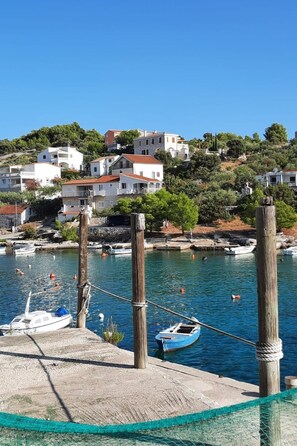 Un pueblo costero con edificios en una colina, un muelle con barcos y un cielo azul despejado.