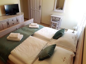 Une chambre d’hôtel avec deux lits, une télévision, une armoire et une petite table avec une lampe.