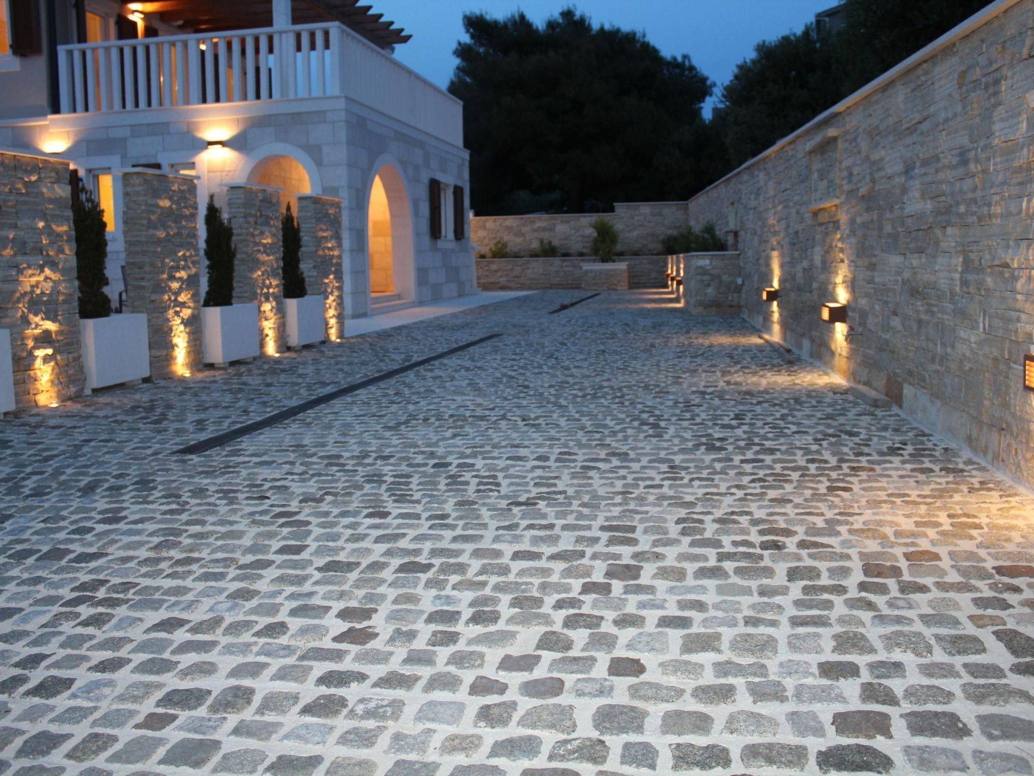A cobblestone pathway leading to a building with stone walls and arched windows.