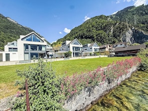 A modern hotel with multiple buildings, a well-maintained lawn, and a clear stream. - Villa am See 3 - Beach House by Interhome (Sisikon)