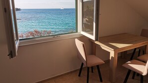 Ett rum med ett stort fönster med utsikt över havet, ett träbord och två stolar.