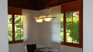 Un interior moderno con una mesa redonda, sillones blancos y ventanas amplias con vistas a zonas verdes.