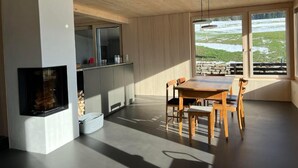 A modern interior with a dining area, kitchen, and a fireplace.