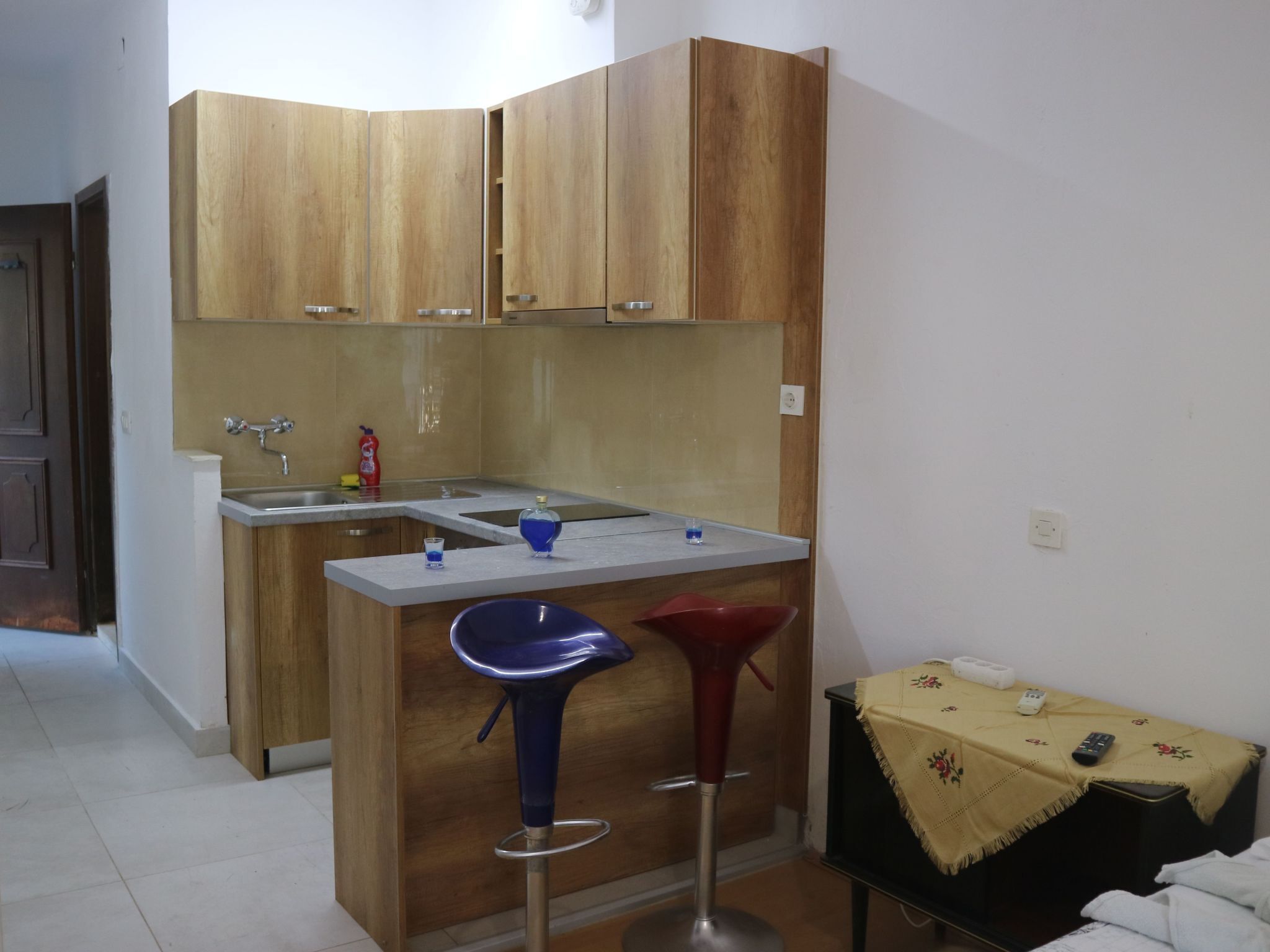 A small kitchen with wooden cabinets, a sink, and a bar stool.