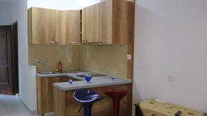 Una pequeña cocina con armarios de madera, un lavamanos y un taburete.