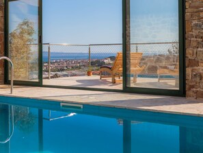 Zona de piscina con vista a un pueblo y un muro de piedra.