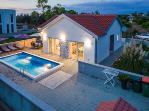 Ein modernes Haus mit Swimmingpool, Sitzgelegenheit im Freien und Blick auf die Umgebung.