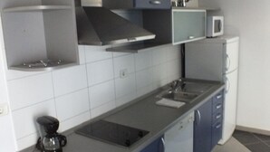 Una cocina moderna con armarios grises y azules, una campana de acero inoxidable, un microondas y una cafetera.