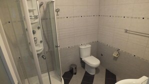 Un baño con ducha de vidrio, inodoro y lavamanos.