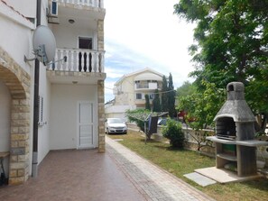 Ein Wohngebäude mit einer Stein-Fassade, einem Balkon mit weißen Balustraden und einer Satellitenschüssel.