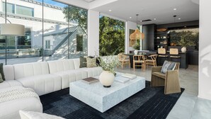 Ett modernt vardagsrum med en vit soffa, ett soffbord i marmor och en matplats med trästolar och ett bord.