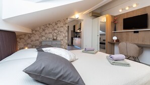 A modern bedroom with a large bed, a TV mounted on the wall, and a small seating area. - Pension Tina Appartement 2 by Interhome (Krk/Šilo)