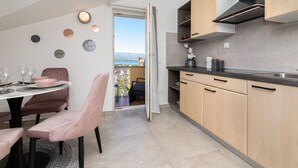 A modern kitchen with wooden cabinets, a black countertop, and a view of the outdoors. - Pension Tina Appartement 2 by Interhome (Krk/Šilo)