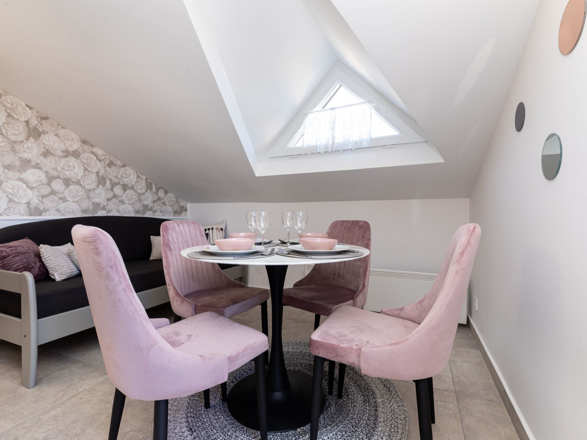 Een eetgedeelte met een ronde tafel, roze stoelen en een dakraam erboven.