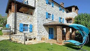 A stone house with blue shutters, a patio, and a blue swing chair. - Vacation home Simone by Interhome (Dracevac)
