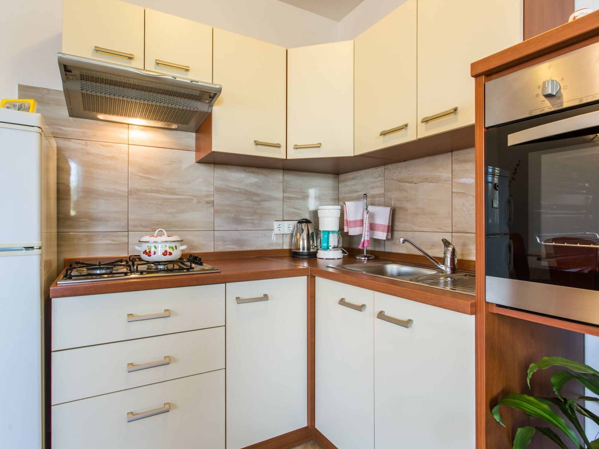 A compact kitchen with white cabinets, a gas stove, a built-in oven, and a coffee maker.