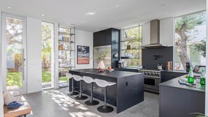 Una cucina moderna con isola centrale, sgabelli da bar e un'ampia finestra.