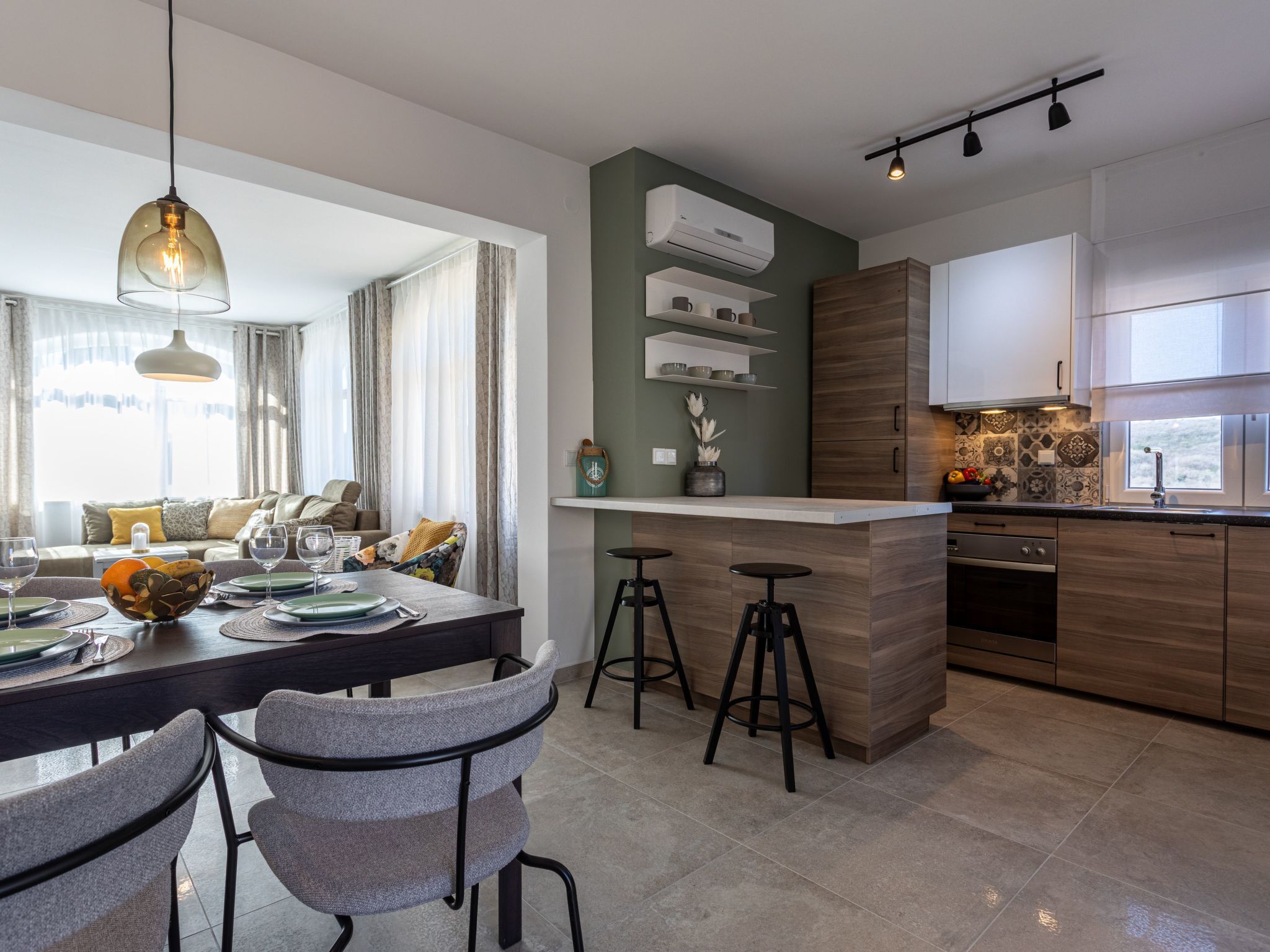 A modern kitchen with a central island, bar stools, and a dining area with a table set for four.