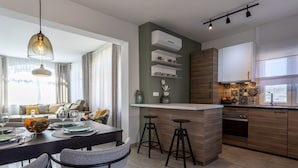 Et moderne køkken med en central ø, barstole og et spiseområde med et bord dækket til fire personer.