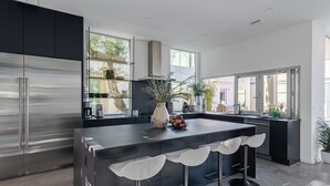 Cozinha moderna com uma ilha grande, eletrodomésticos de aço inoxidável e banquetas.