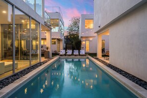 Ein moderner Poolbereich mit Glaswänden, Liegestühlen und Blick zum Himmel.