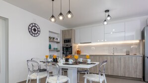 A modern kitchen with white cabinets, a central island, and pendant lighting. - Moderne Wohnung Grzetic by Interhome (Krk/Šilo)