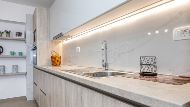 A modern kitchen with a marble countertop, stainless steel sink, and wooden cabinets. - Moderne Wohnung Grzetic by Interhome (Krk/Šilo)