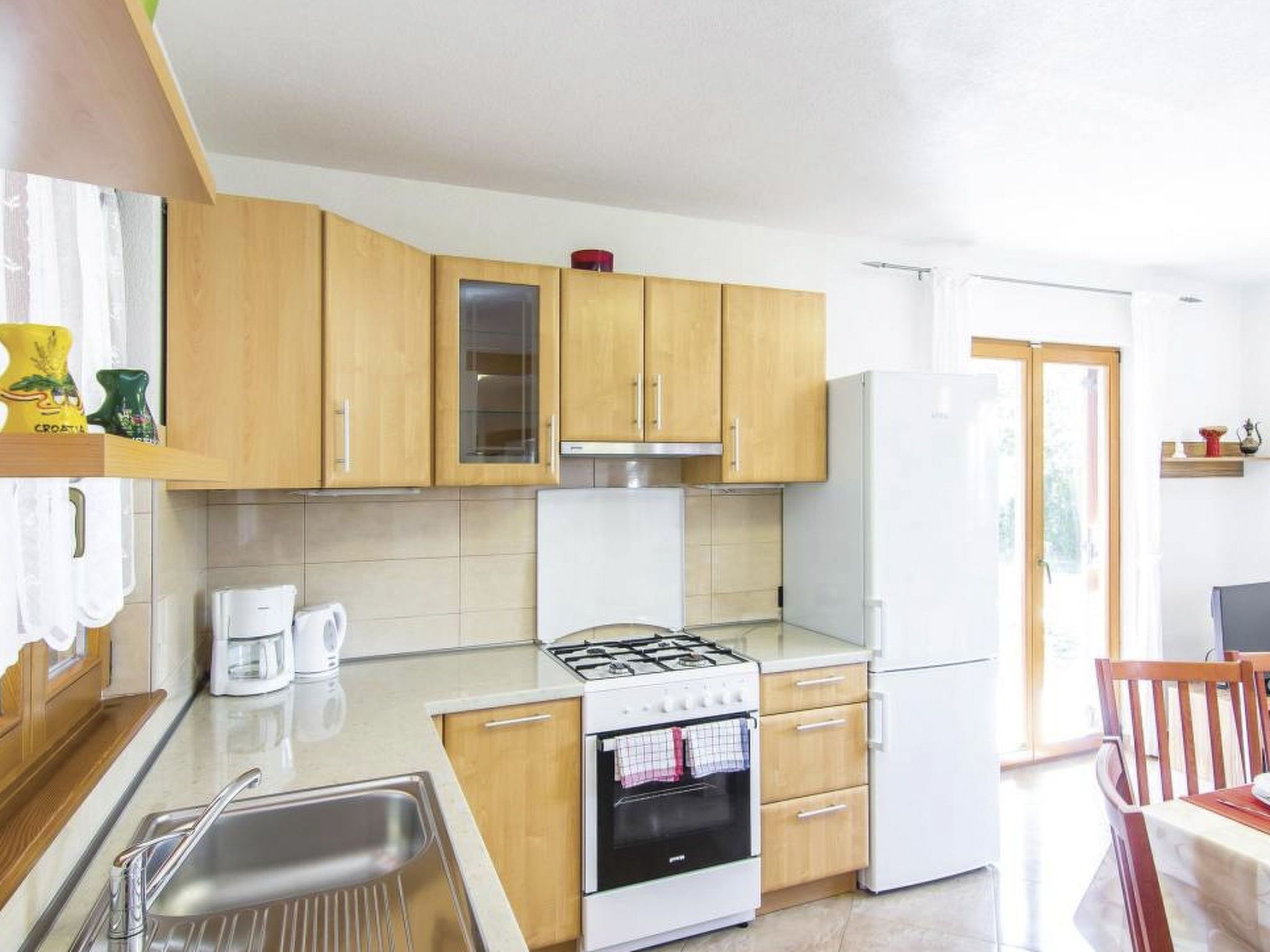A compact kitchen with wooden cabinets, a gas stove, a refrigerator, and a coffee maker.