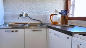 Una cocina con un lavamanos doble, un hervidor y un lavavajillas.