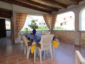 A covered outdoor dining area with a table set for four, surrounded by white chairs, and a blue tablecloth. - Apartment Andjela by Interhome (Krk/Šilo)