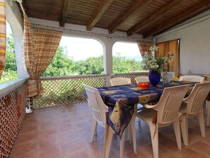 An outdoor patio with a table and chairs, a view of greenery, and a wooden ceiling. - Apartment Andjela by Interhome (Krk/Šilo)