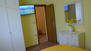 Ein Schlafzimmer mit Bett, Kleiderschrank, Kommode, Spiegel und Fernseher, der eine Naturansicht zeigt.
