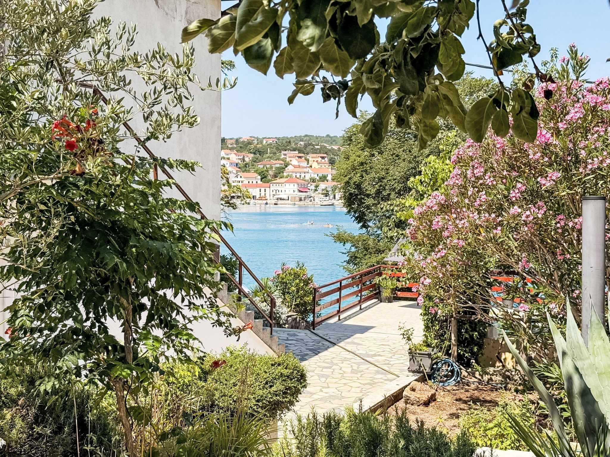 A coastal pathway leading to a body of water with a view of a town in the distance.
