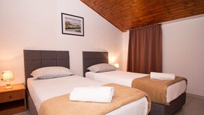 Een hotelkamer met twee bedden, een houten plafond en een lijst met een afbeelding aan de muur.