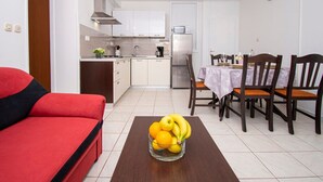 Een ruimtelijk ingerichte leefruimte met een kitchenette, een eethoek en een rode bank.