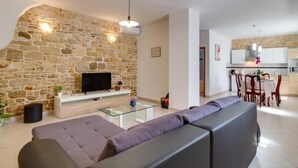 Una sala de estar moderna con una pared de piedra, un televisor de pantalla plana y una mesa de centro de vidrio.